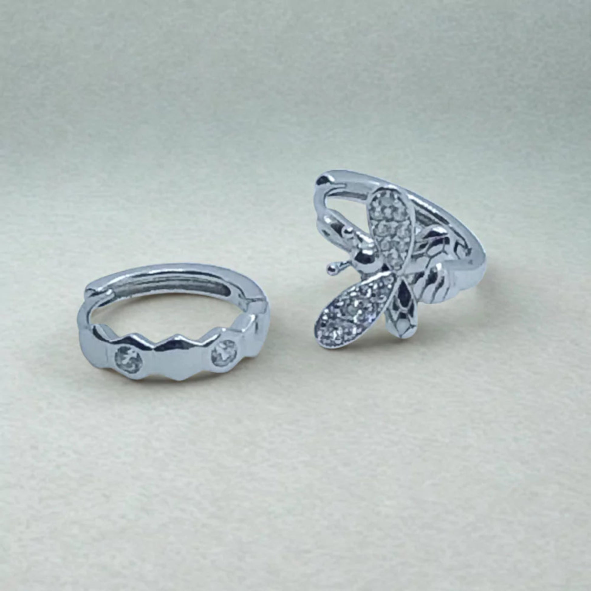 Asymmetric Sterling Silver Huggie Hoop Earrings with sparkly zircon stones on a light gray background
