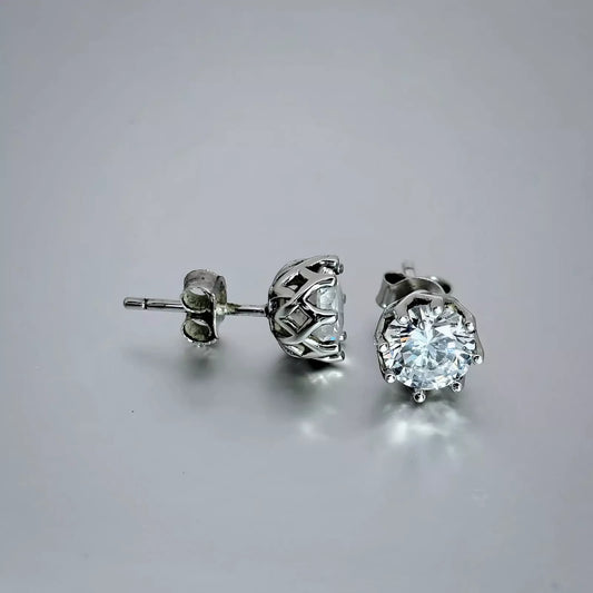 A pair of silver stud earrings crafted in sterling silver 925 features clear cubic zirconia gems on a light grey background.