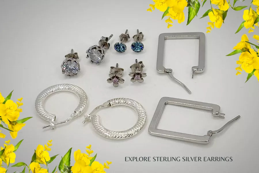 Collection of sterling silver earrings, hoops and studs on a light grey background with yellow spring flowers.
