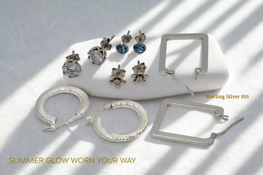 Sterling silver 925 earrings featuring cubic zirconia stud earrings, creole hoop earrings and geometric hoop earrings displayed on a soft white-grey background with subtle summer styling.