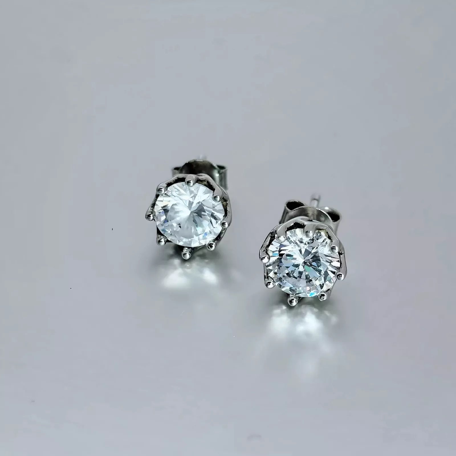 A pair of Cubic Zirconia Earrings crafted in Sterling Silver 925,  round clear stone on a grey background.