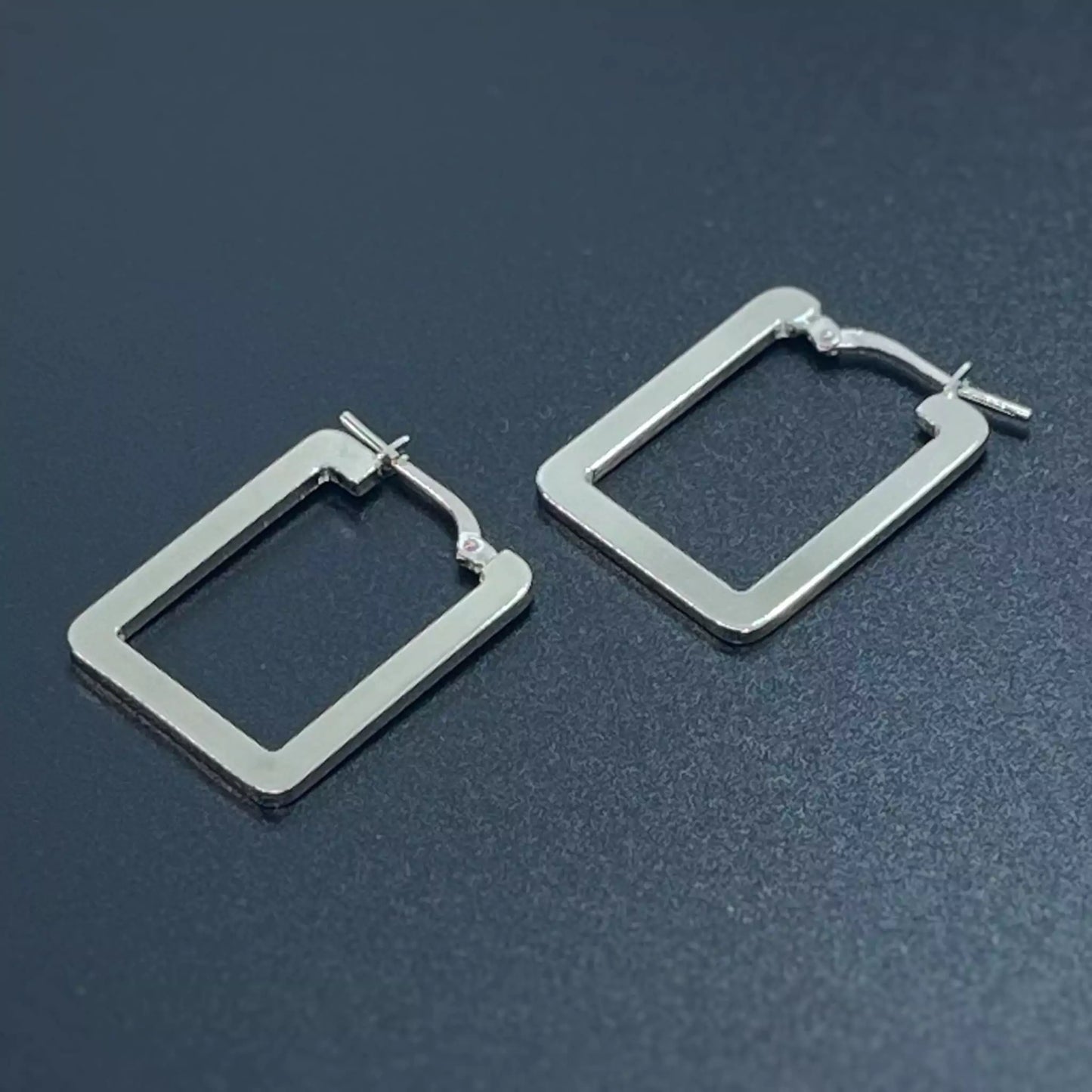 Pair of rectangle silver hoop earrings on a dark background