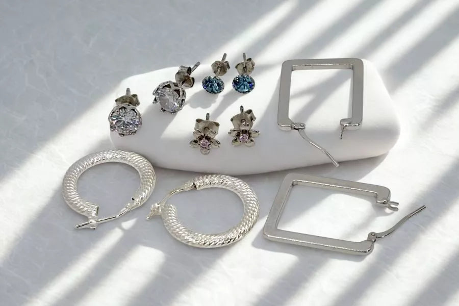 Collection of silver earrings, studs and hoops on a light background