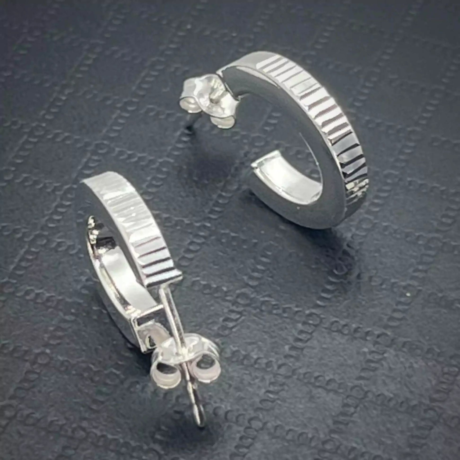 Pair of Stunning Ribbed Lobe Stud Hoop Sterling Silver Earrings on a textured dark surface 